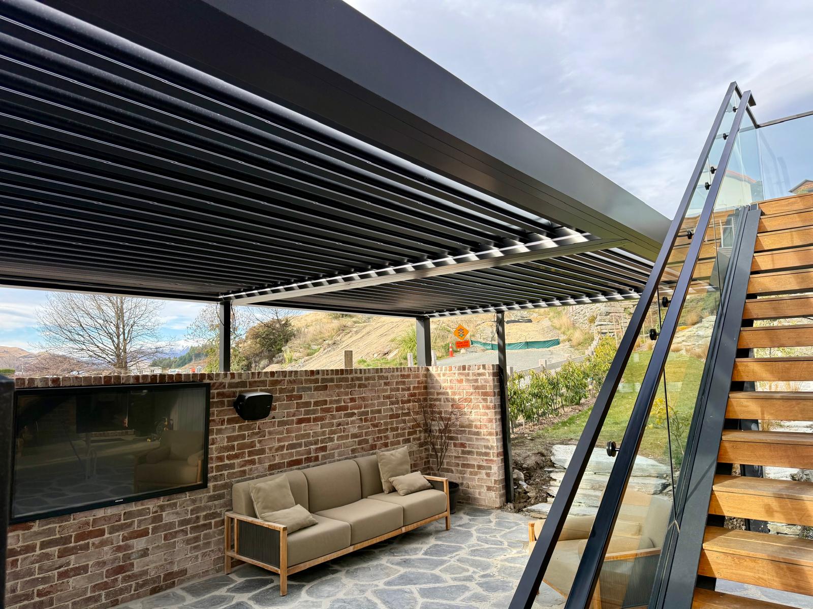 Black louvre roof over a brick outdoor living area in Queenstown