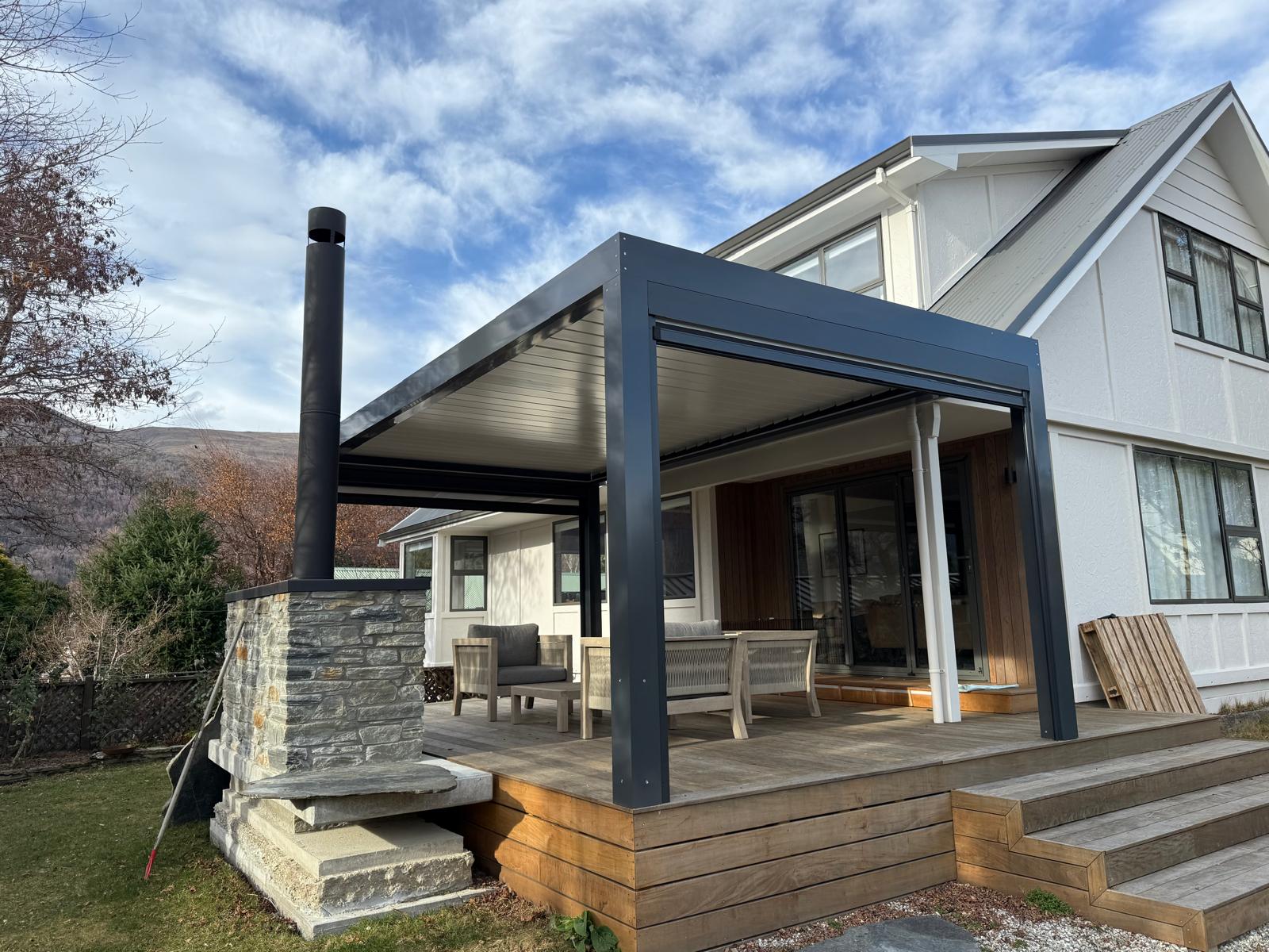 Grey louvre roof attached to a home beside a schist chimney in Queenstown