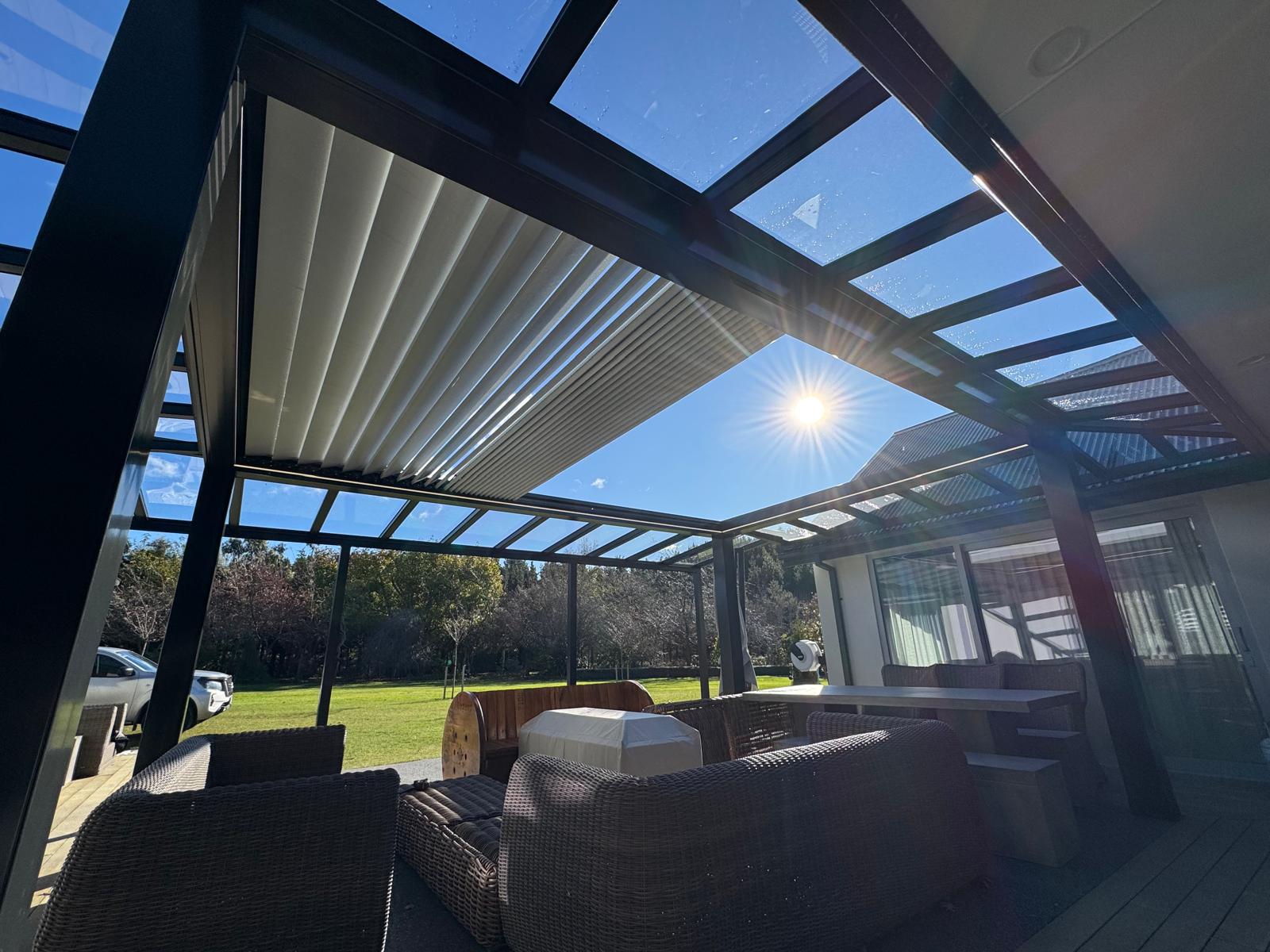 White louvres opening to the sun under a glass-roofed pergola