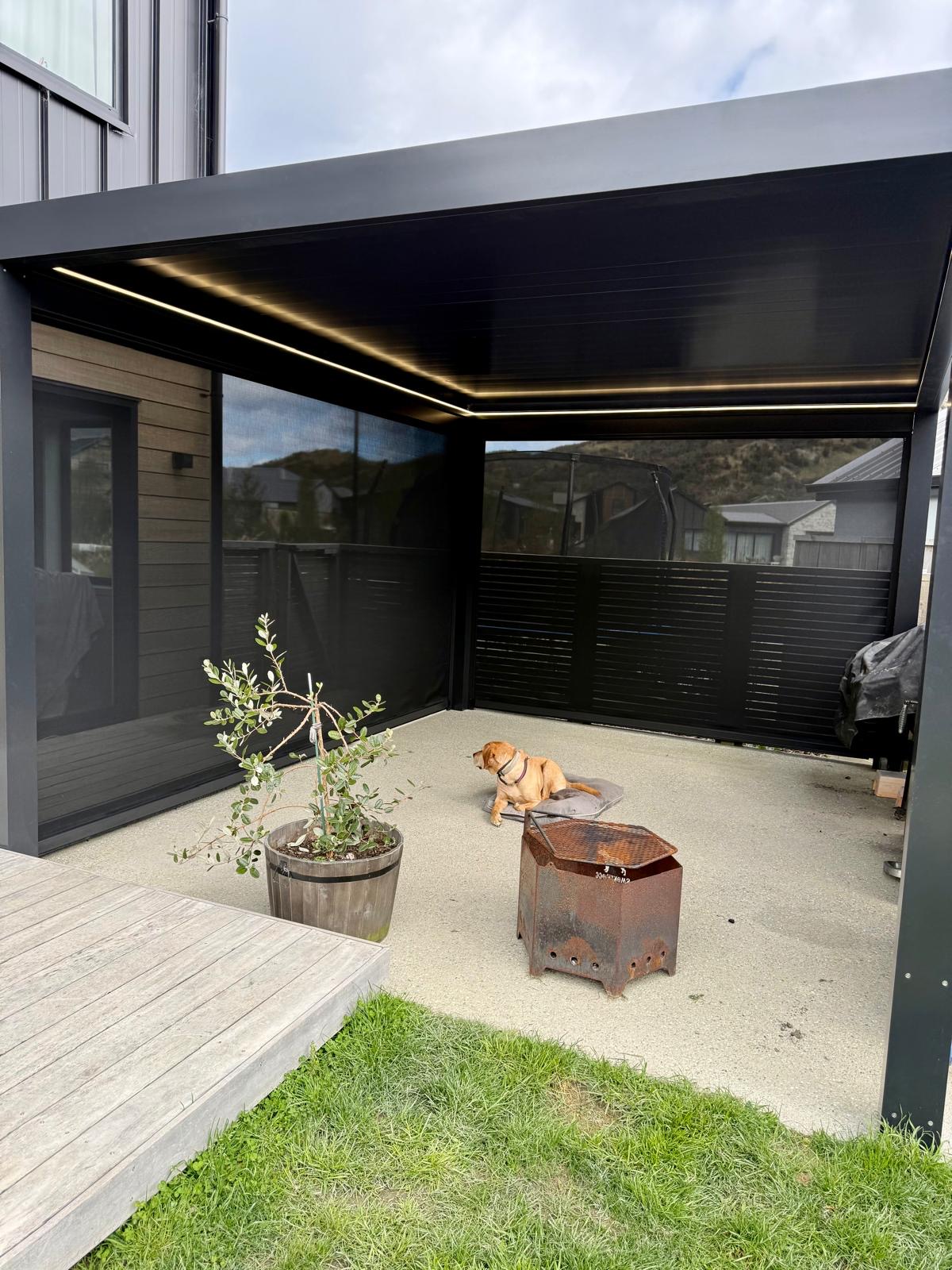 Black louvre roof with LED lighting and outdoor blinds over a courtyard in Queenstown