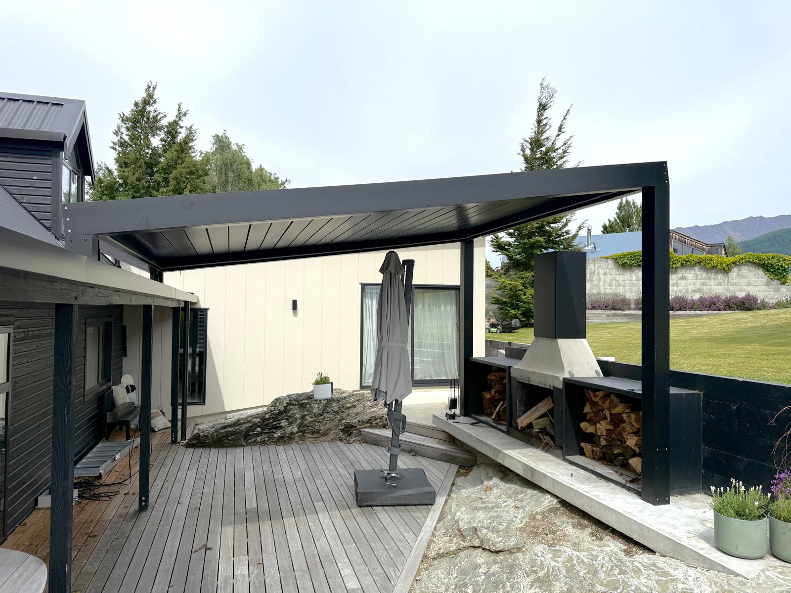 Black louvre roof over a deck and outdoor fireplace in Queenstown