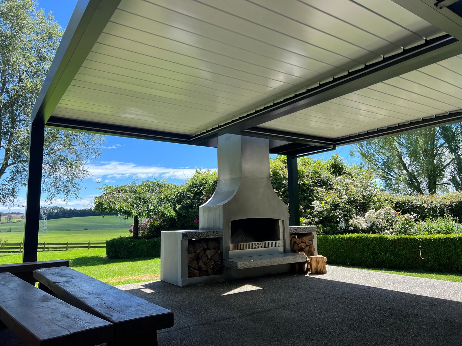 White louvre roof over an outdoor fireplace and entertaining area