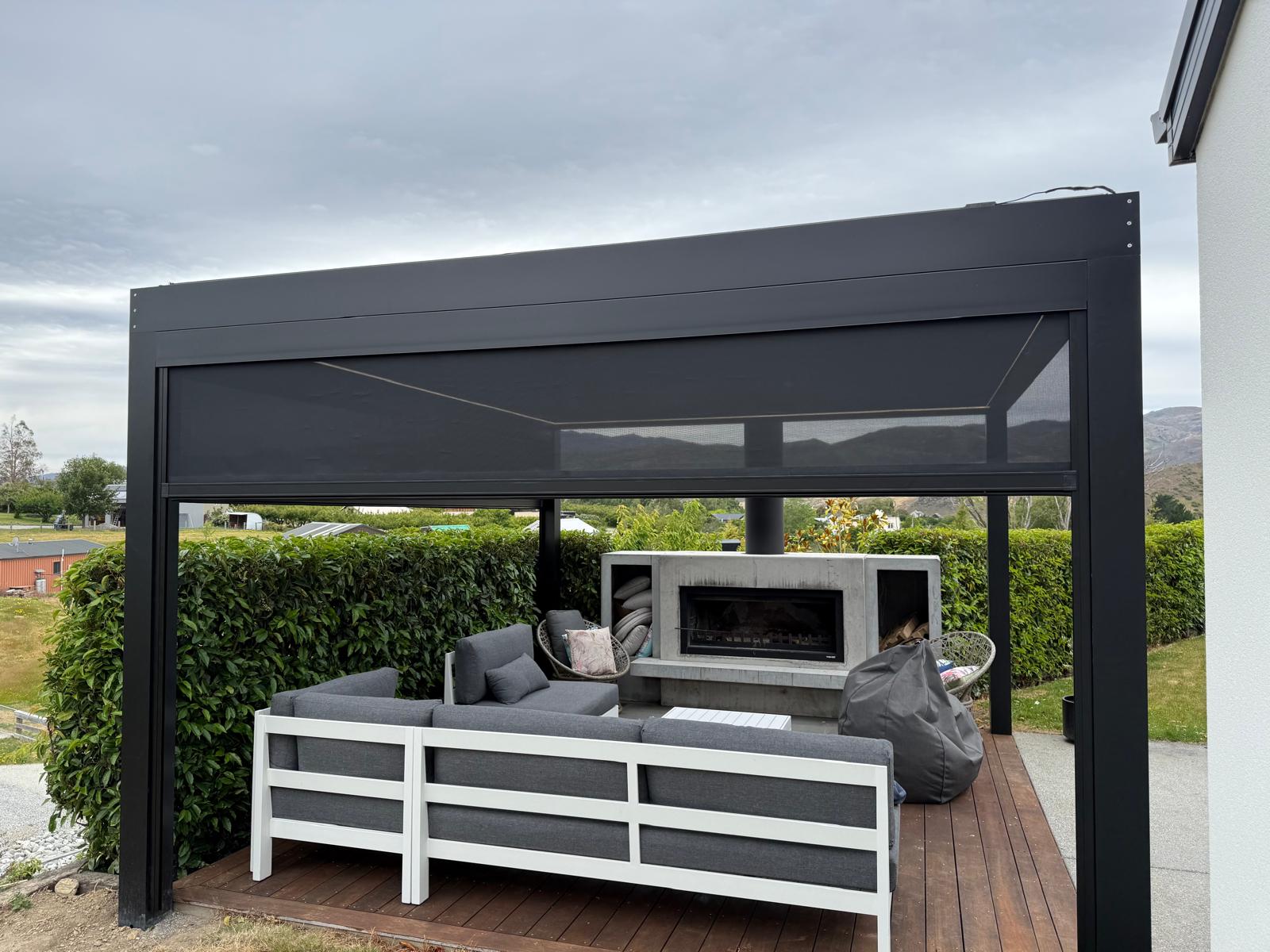 Outdoor blind lowered on a black louvre roof in Central Otago